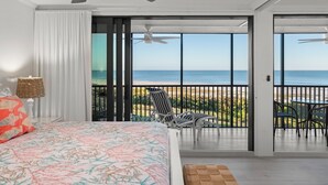 A bedroom with a bed, a ceiling fan, a lamp, and a view of the beach through large sliding doors. - Sundial A203 - Stunning, Gulf Front, 1 bedroom Condo on Sanibel Island! (Sanibel)