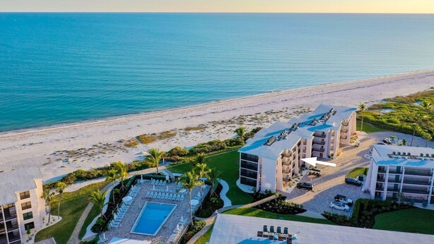 A beachfront hotel with a swimming pool, multiple balconies, and a view of the ocean. - Sundial A203 - Stunning, Gulf Front, 1 bedroom Condo on Sanibel Island! (Sanibel)