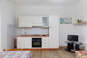 A compact kitchen with white cabinets, a gas stove, and a built-in oven. - Apartment 'Via Gorizia 8 - Verde' with Shared Garden, Wi-Fi and Air Conditioning (Cecina)