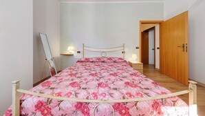 A bedroom with a bed, bedside lamps, a wooden door, and a hallway. - Apartment 'Via Gorizia 8 - Verde' with Shared Garden, Wi-Fi and Air Conditioning (Cecina)