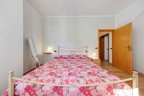 Ein Schlafzimmer mit einem Bett, Nachttischlampen, einer Holztür und einem Flur.