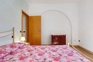 Une chambre à coucher comprenant un lit, une armoire en bois, une table de chevet avec une lampe et une commode.