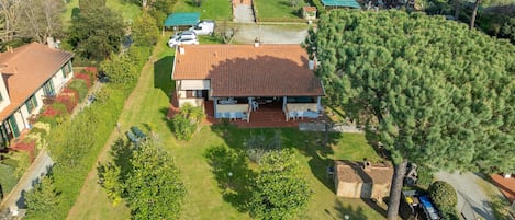 A residential property with a large house, a covered patio, and a well-maintained garden.
