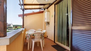 A balcony with a table and chairs, a power outlet, and a window with blinds. - Apartment 'Via Gorizia 8 - Verde' with Shared Garden, Wi-Fi and Air Conditioning (Cecina)
