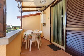Ein Balkon mit Tisch, Stühlen, einer Steckdose und einem Fenster mit Jalousien.