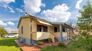 Ein zweigeschossiges Haus mit Terrasse, ein Auto vor der Tür und ein klarer Himmel.