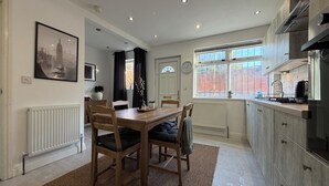 A modern kitchen with a dining area, featuring a wooden table, chairs, and a radiator.