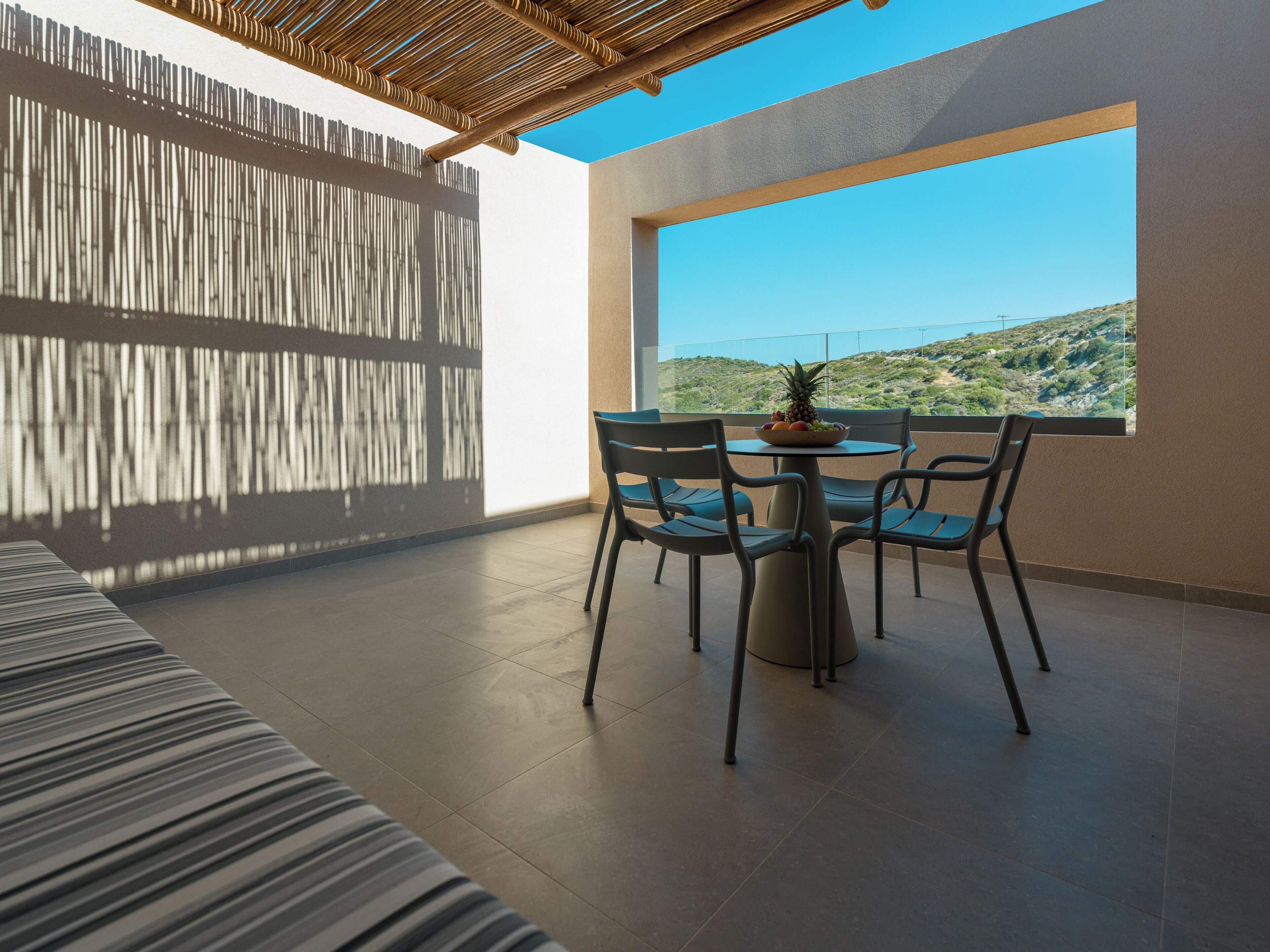 A modern outdoor dining area with a view of a hilly landscape.