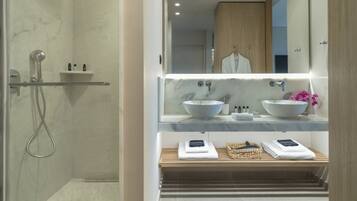 A modern bathroom with a walk-in shower, two sinks, and a vanity with a mirror.