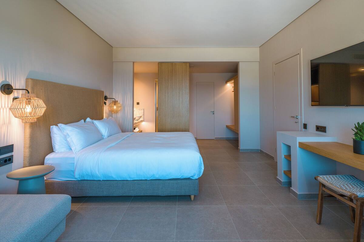 Un dormitorio moderno con una cama grande, mesitas de noche, un escritorio y una silla.