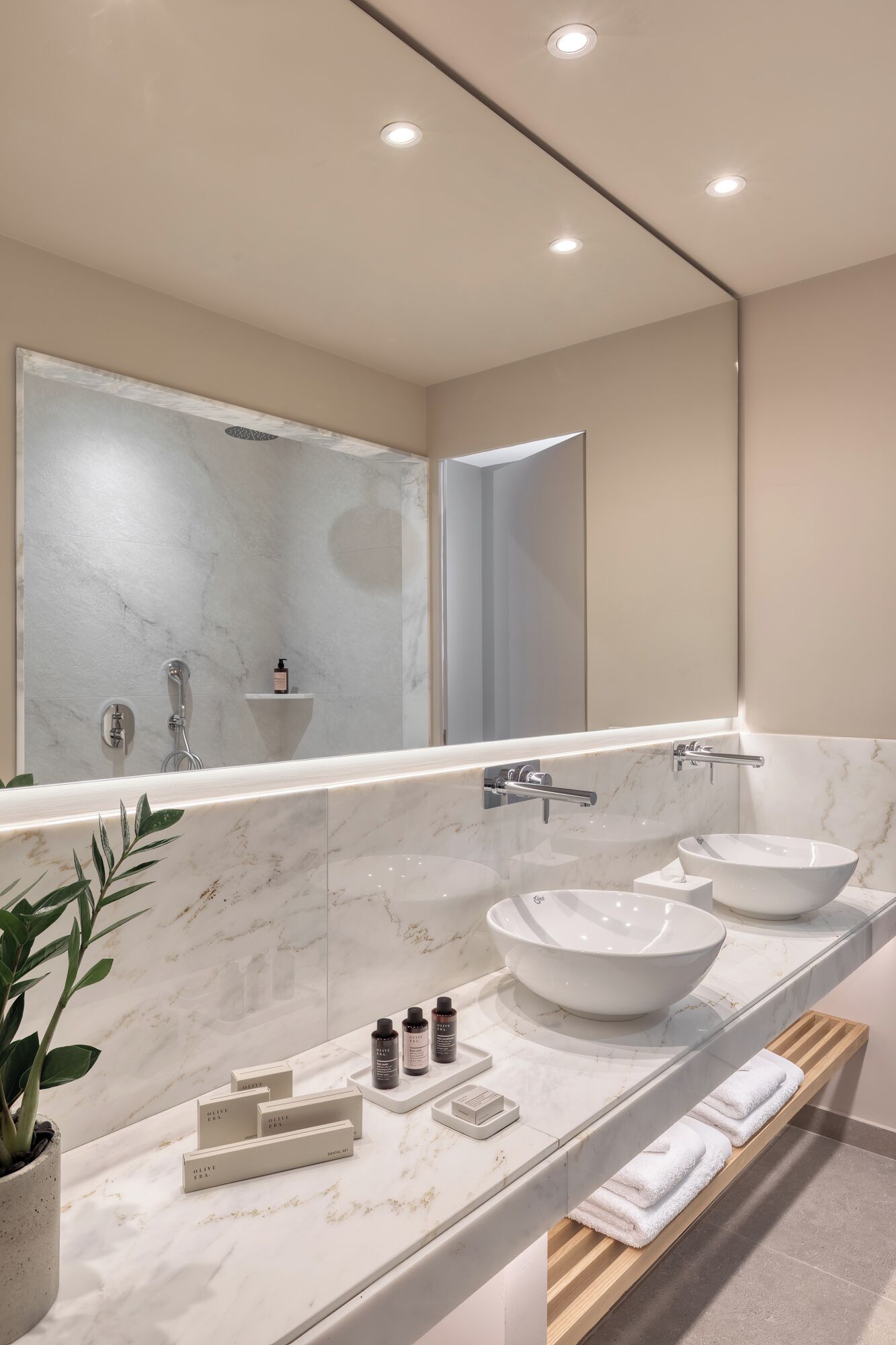 Ein modernes Badezimmer mit einem großen Spiegel, zwei Waschbecken und einer Dusche.