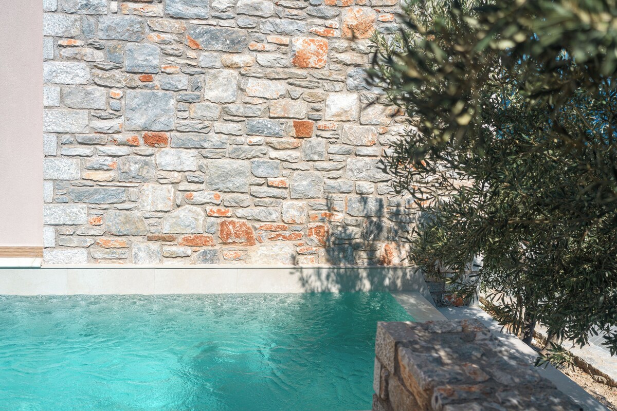 A stone wall with a pool and a tree.