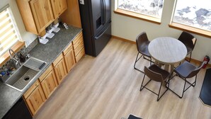 A kitchen with wooden cabinets, a stainless steel sink, a black refrigerator, and a round table with four chairs. - Sunflower Cabin • Modern Family Retreat • Easy Access • Pets OK • 1.2 Acres (Jefferson)