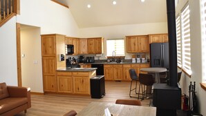 A spacious kitchen with wooden cabinets, a central island, and a dining area with a table and chairs. - Sunflower Cabin • Modern Family Retreat • Easy Access • Pets OK • 1.2 Acres (Jefferson)