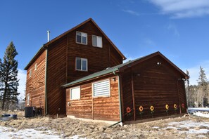 A two-story wooden cabin with a large garage and a covered porch. - Sunflower Cabin • Modern Family Retreat • Easy Access • Pets OK • 1.2 Acres (Jefferson)
