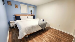 Un dormitorio con cama, mesita de noche y ventana con persianas.