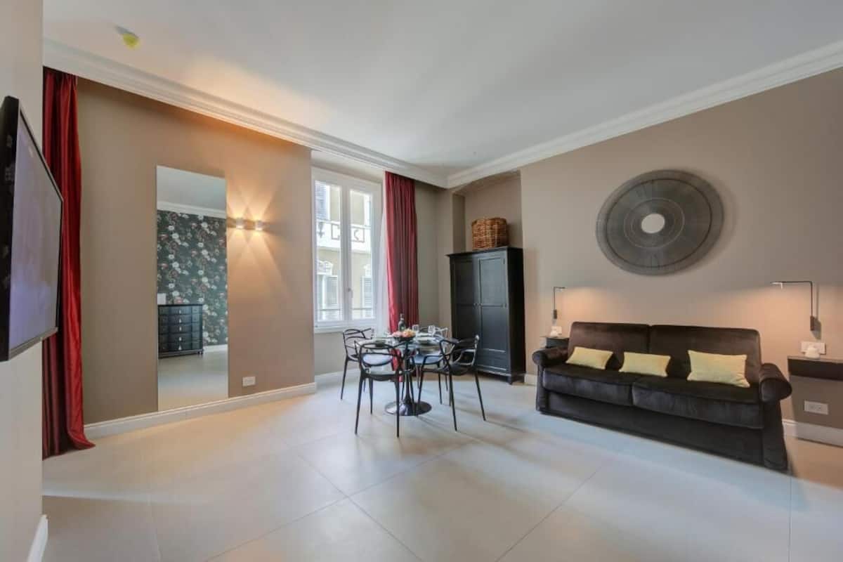 A modern living room with a dining table, a sofa, and a TV.