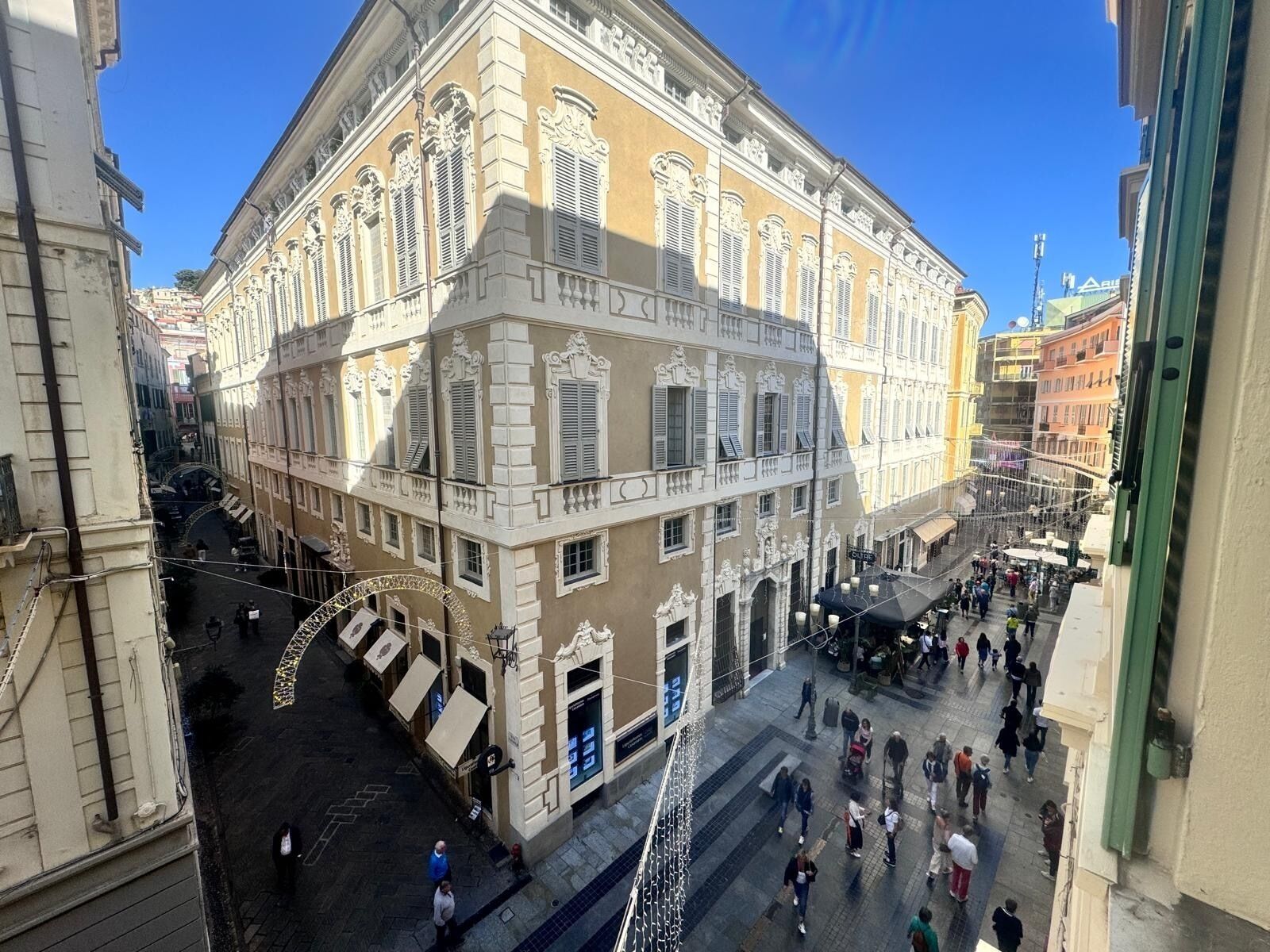 Ein historisches Gebäude mit klassischer Architektur, einem zentralen Innenhof und einer belebten Straßenszene.
