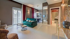 A modern living room with a green sofa, leopard print armchairs, and a dining area with a table and chairs. - SEVEN SUITES APARTMENTS SANREMO (Sanremo)
