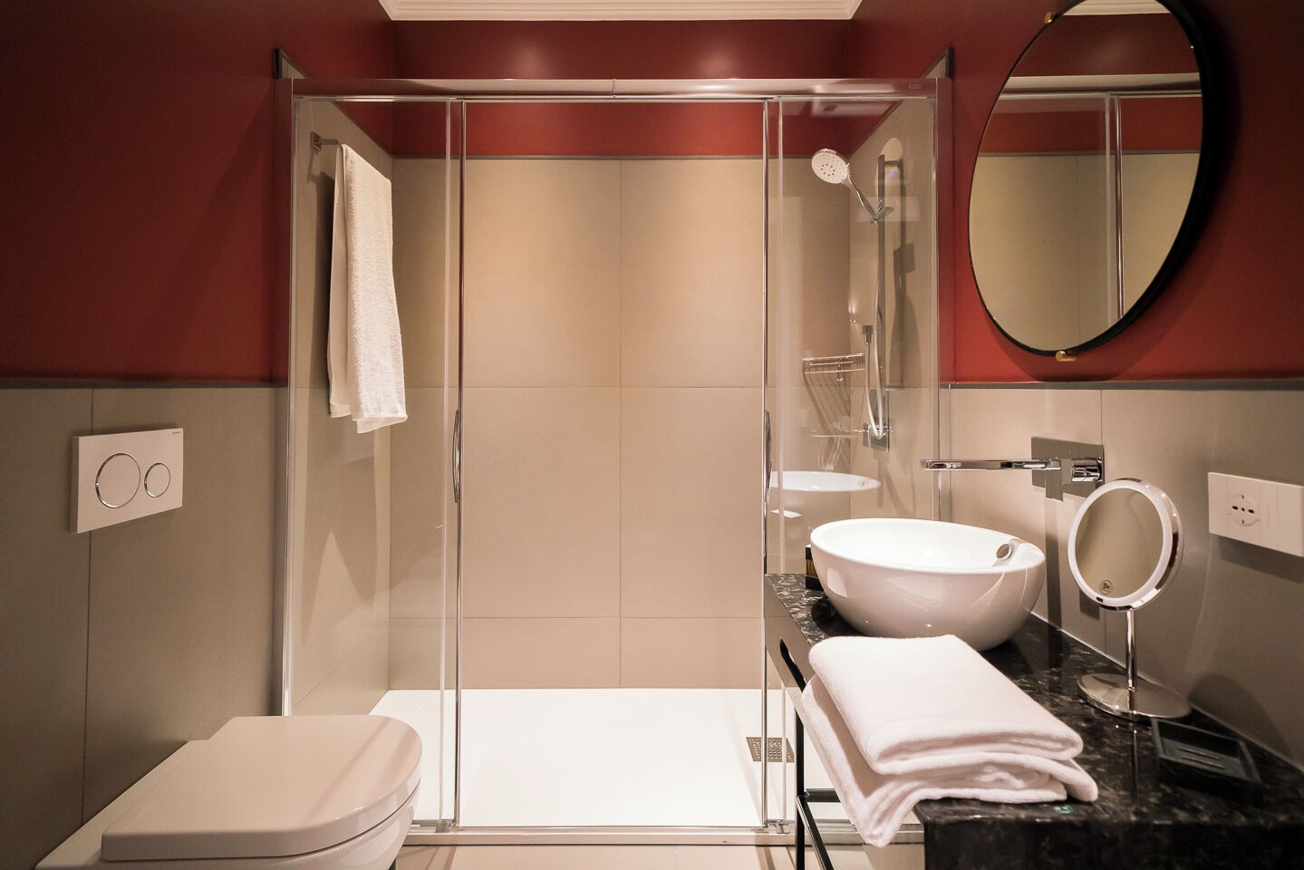Un baño moderno con ducha de vidrio, un lavabo blanco y un inodoro.