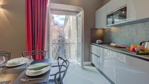 A modern kitchen with white cabinets, a microwave, and a dining area with a table set for two. - SEVEN SUITES APARTMENTS SANREMO (Sanremo)