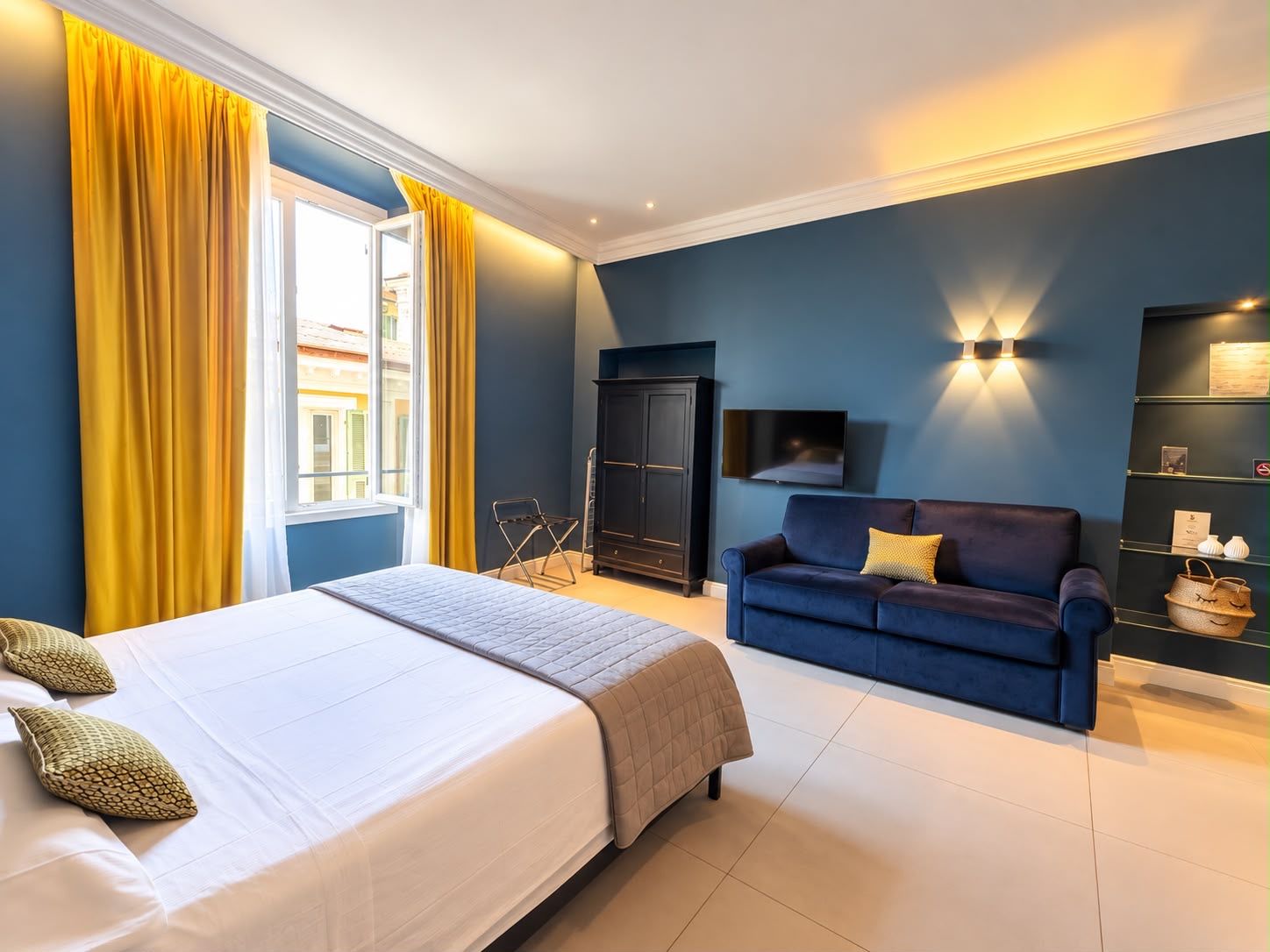 A hotel room with a bed, a blue sofa, a TV, and a wardrobe.