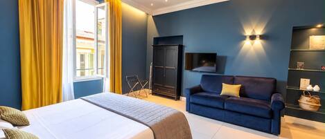 A hotel room with a bed, a blue sofa, a TV, and a wardrobe.
