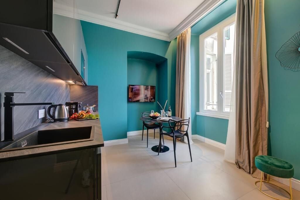 A modern kitchen with a built-in stove, a dining area with a table and chairs, and a window with curtains.