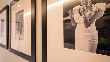 A wall with framed photographs and a single large framed photo of a person in a white dress.