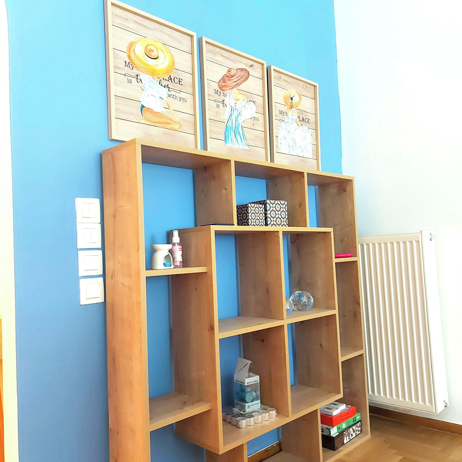 A wooden shelving unit with decorative items and a few small boxes against a blue wall.