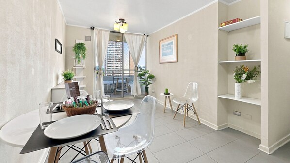 Un espace repas moderne avec vue sur le balcon, une table à manger avec des chaises et une étagère ornée de plantes.
