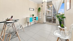 A modern living room with a dining area, a balcony with a view, and a small white cabinet with blue doors. - Oceana Suites Estacion Central (Santiago)