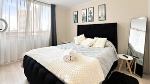 Een hotelkamer met een bed, een ronde spiegel en een tafeltje.