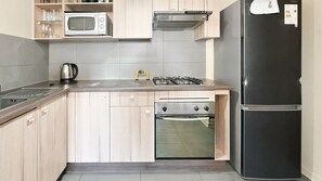 A modern kitchen with a built-in microwave, gas stove, oven, and a black refrigerator. - Oceana Suites Estacion Central (Santiago)