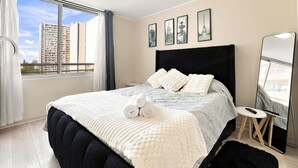 Une chambre d’hôtel avec un grand lit, une table ronde et une vue sur les immeubles par la fenêtre.