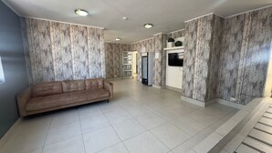Um quarto amplo com sofá, televisão e frigorífico.