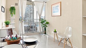 Un intérieur moderne avec un balcon, un coin repas et une vue sur le paysage urbain.
