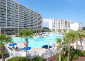 Un hotel con varios balcones, piscina y palmeras.