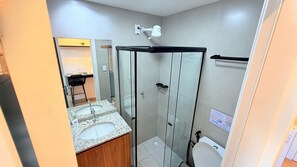 A modern bathroom with a glass-enclosed shower, a sink with a marble countertop, and a toilet. - Concept Life Stella (Salvador)