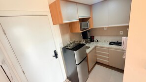 A compact kitchen with a refrigerator, microwave, and a coffee maker on the countertop. - Concept Life Stella (Salvador)