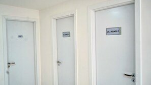 Three white doors with labels indicating 'SALA REUNIÃO 1' and 'SALA REUNIÃO 2'.