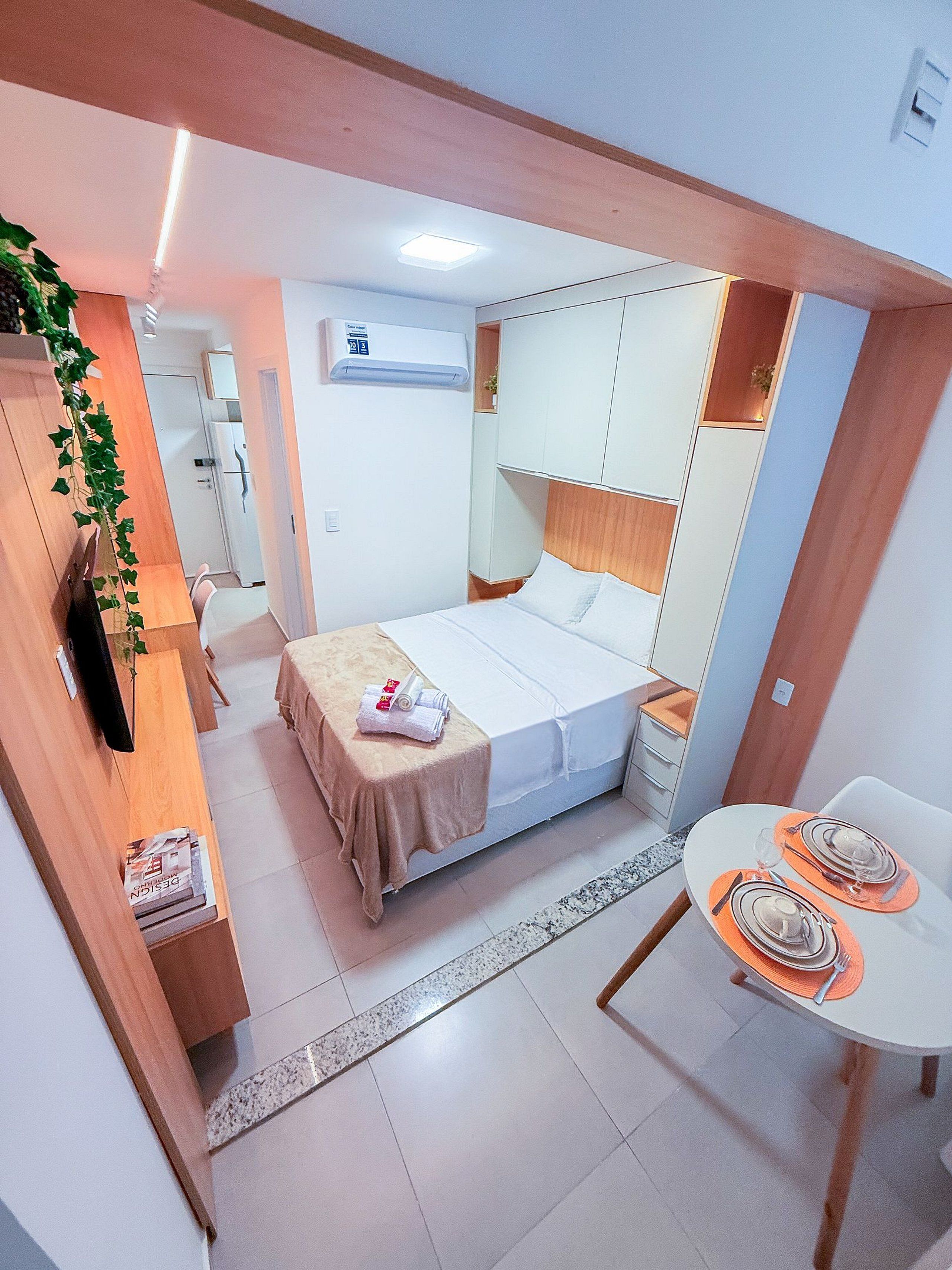 Una habitación de hotel moderna con cama, mesita de noche y una pequeña zona de comedor.