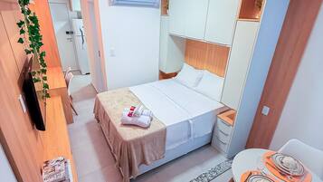 Una habitación de hotel moderna con cama, mesita de noche y una pequeña zona de comedor.