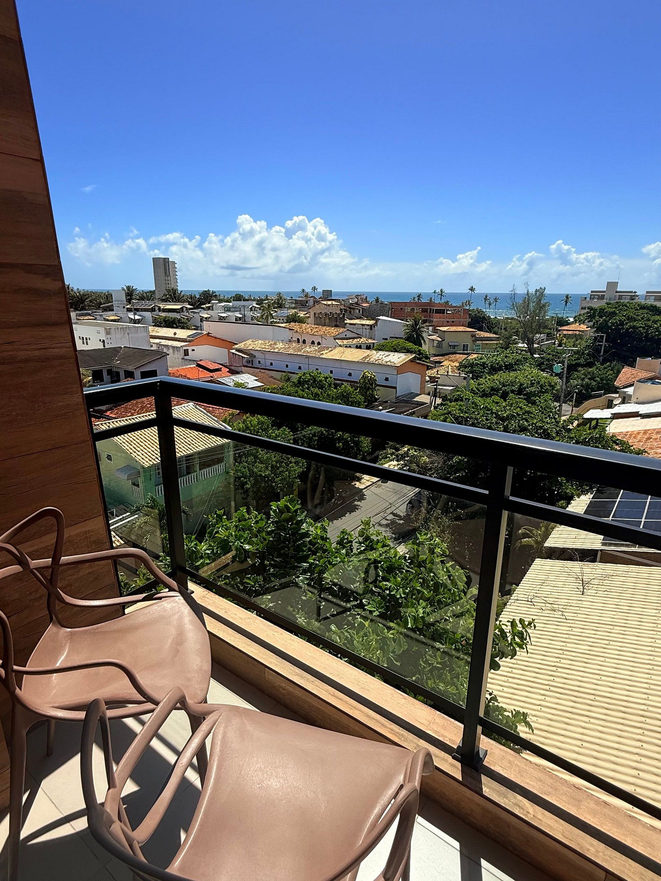 A balcony with a view of a cityscape, including buildings and a body of water.