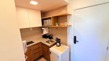 Cocina compacta con microondas, cafetera y un refrigerador pequeño.