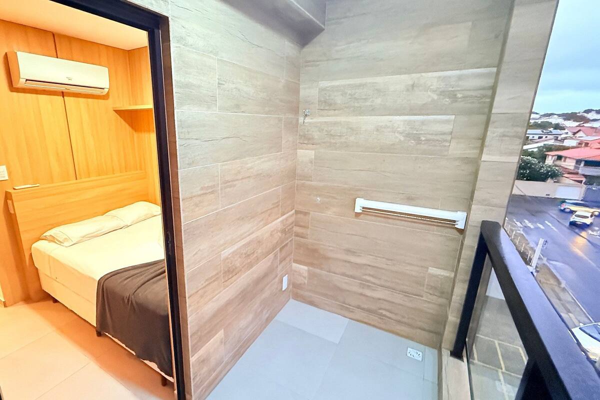 Una habitación pequeña y moderna con cama, un armario de madera y zona de ducha.