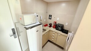 A compact kitchenette with a white refrigerator, a microwave, a coffee maker, and a toaster. - Concept Life Stella (Salvador)