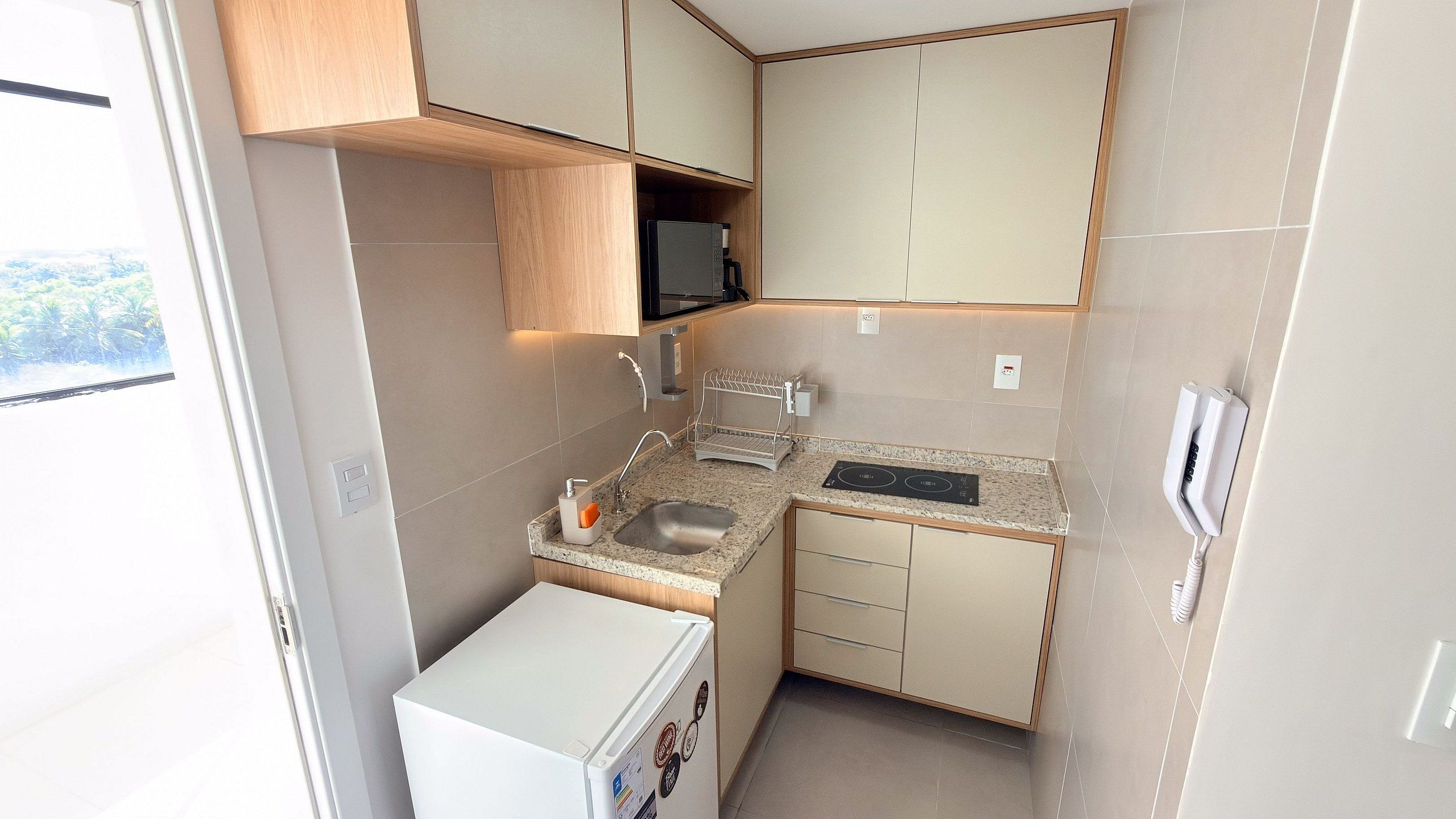 A compact kitchen with a sink, countertop, and a small refrigerator.