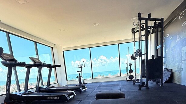 A gym with treadmills, a stationary bike, and a squat rack. - Concept Life Stella (Salvador)