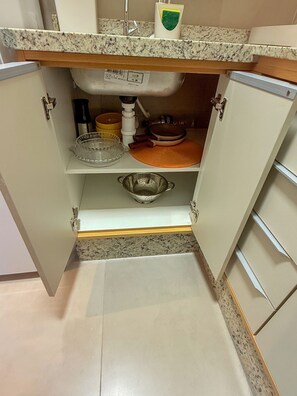 Una cocina con encimera de granito, un lavamanos, un colador y un escurreplatos.